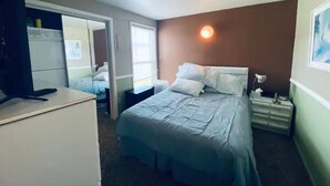 A hotel room with a bed, bedside table, lamp, and a desk with a computer. - #168 Condo near large pool & shuttle to Gorge Amp-book separately (Quincy)