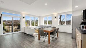 A modern kitchen with a dining area, large windows, and a view of the outdoors. - Long Shadow - MTB Oasis (Bella Vista)
