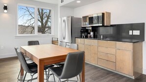 A modern kitchen with a wooden table and chairs, a refrigerator, microwave, and cabinets. - Long Shadow - MTB Oasis (Bella Vista)