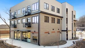A modern multi-story building with balconies, a fire pit, and a landscaped courtyard. - Long Shadow - MTB Oasis (Bella Vista)