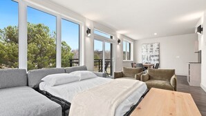 Ein modernes Schlafzimmer mit einem großen Bett, einem grauen Sofa und einem Holztisch.
