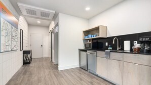 Cozinha moderna equipada com micro-ondas, cafeteira e máquina de lavar loiça.