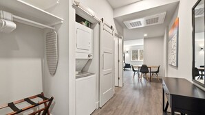 Un couloir avec un banc en bois, une buanderie aux murs blancs et un coin repas avec une table et des chaises.