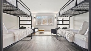 Une chambre avec deux lits superposés, une petite table et une fenêtre.