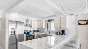 Una cocina moderna con una isla de mármol, electrodomésticos de acero inoxidable y una zona de taburetes con barra.
