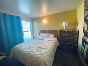 Cozy retreat with a neatly made bed, dresser, and window with blinds.
