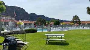 A grassy area with picnic tables, a barbecue grill, and a swimming pool. - #181 Condo near large pool & shuttle to Gorge Amp-book separately (Quincy)