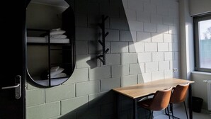 A room with a wooden table and two chairs, a mirror, and a coat rack against a white brick wall. - Ring SPA Hostel (Tallinn)