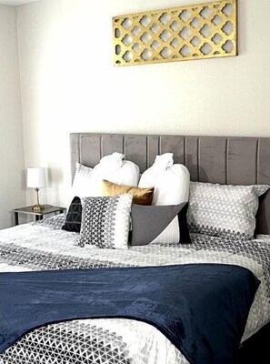 Restful retreat with a neatly arranged bed and a decorative metal piece above.