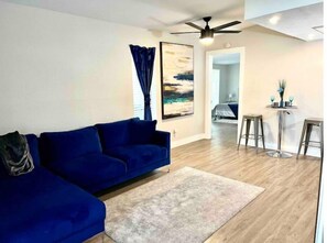Relax in this stylish living room with a comfortable sofa, neutral-toned rug, and a beautiful abstract painting.