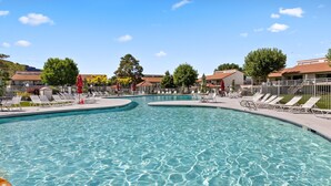 Ein großer, klarer Pool mit mehreren Bahnen, umgeben von Liegestühlen und Sonnenschirmen.