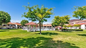 Ein Hotelinnenhof mit Laube, Schwimmbecken und gepflegtem Rasen.