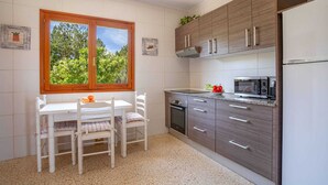 A kitchen with a dining table, chairs, a microwave, and a refrigerator.