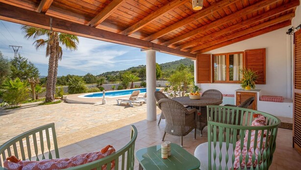 A covered outdoor area with a pool, seating, and a view of the landscape.