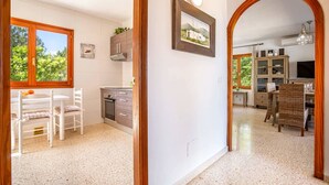 A kitchen with white cabinets, a dining area with a table and chairs, and a hallway with a wooden archway.