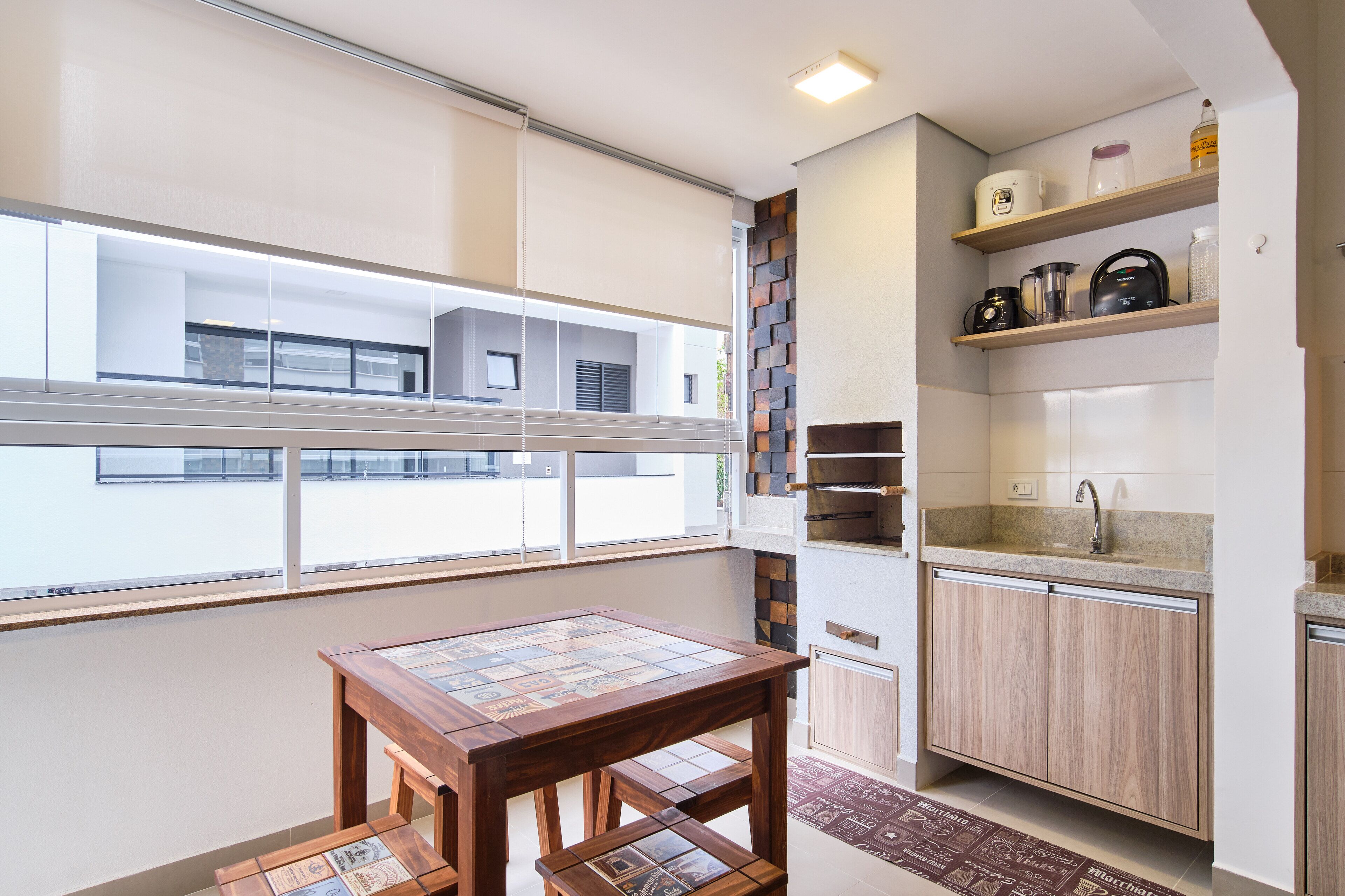 Una cocina compacta con horno integrado, lavamanos y ventana con vistas a un balcón.