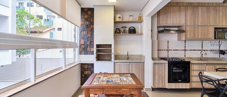 A modern kitchen with a wooden table and stools, a built-in oven, and a view of the outside.