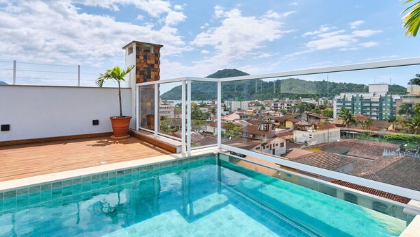 A rooftop swimming pool with a view of a cityscape and mountains. - Edífico Residencial Unique (Ubatuba)