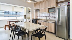 A modern kitchen with a granite countertop, stainless steel appliances, and wooden cabinets. - Edífico Residencial Unique (Ubatuba)