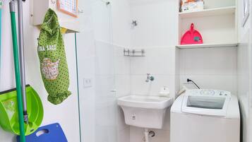 Ein kleines Badezimmer mit Waschbecken, Toilette, Waschmaschine und Dusche.