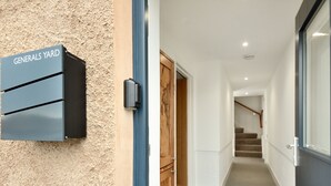 A hallway with a sign reading "Generals Yard" on the left, leading to a wooden door and a staircase. - Generals Yard (Eyemouth)