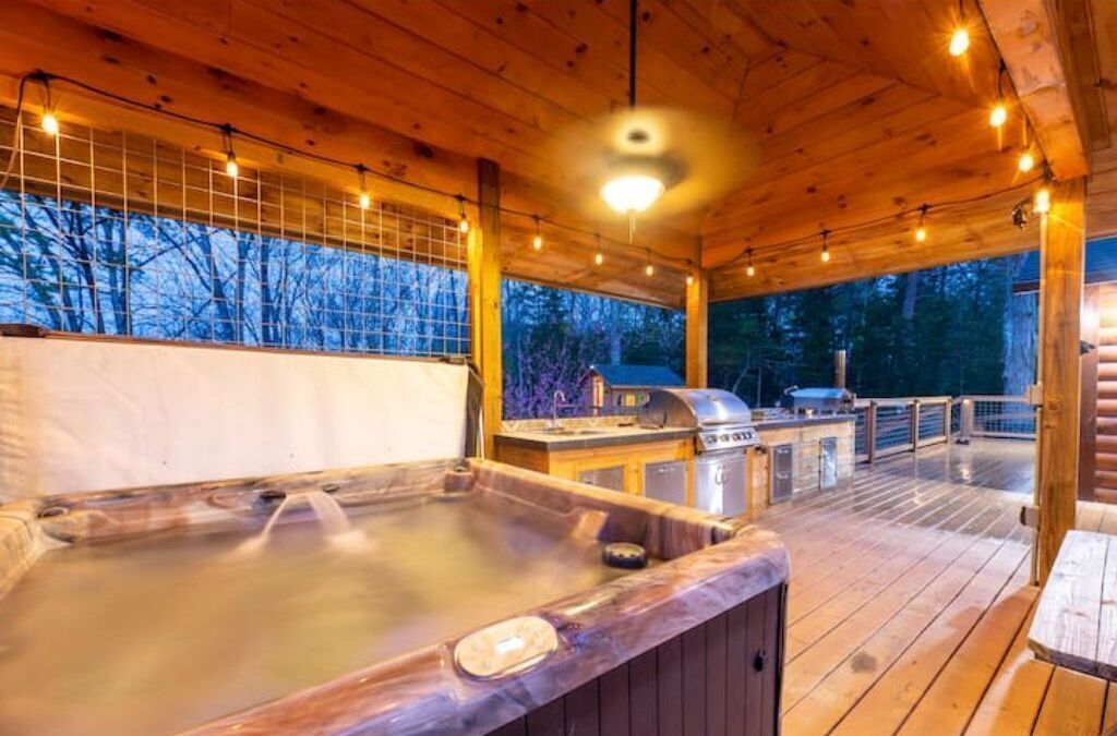 Eine Holzterrasse mit Whirlpool, Grill und Außendusche.