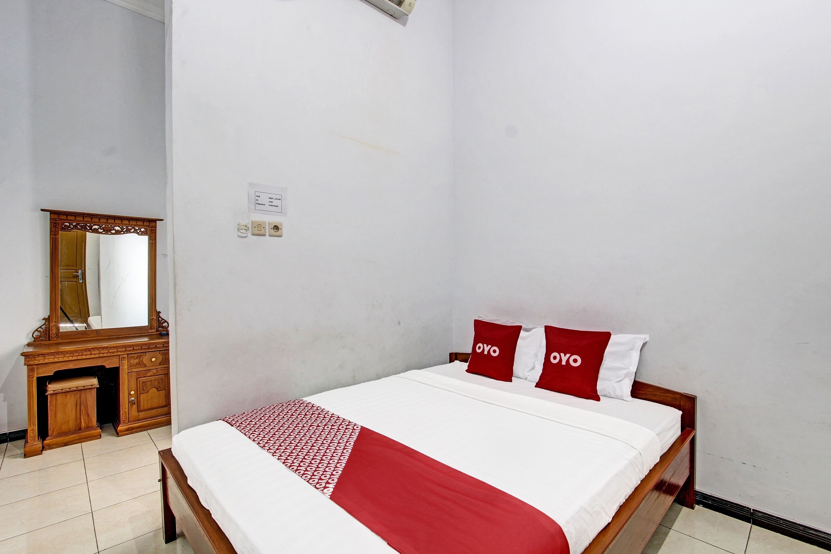 Ein Schlafzimmer mit einem hölzernen Bett, weißer Bettwäsche und roten Kissen.