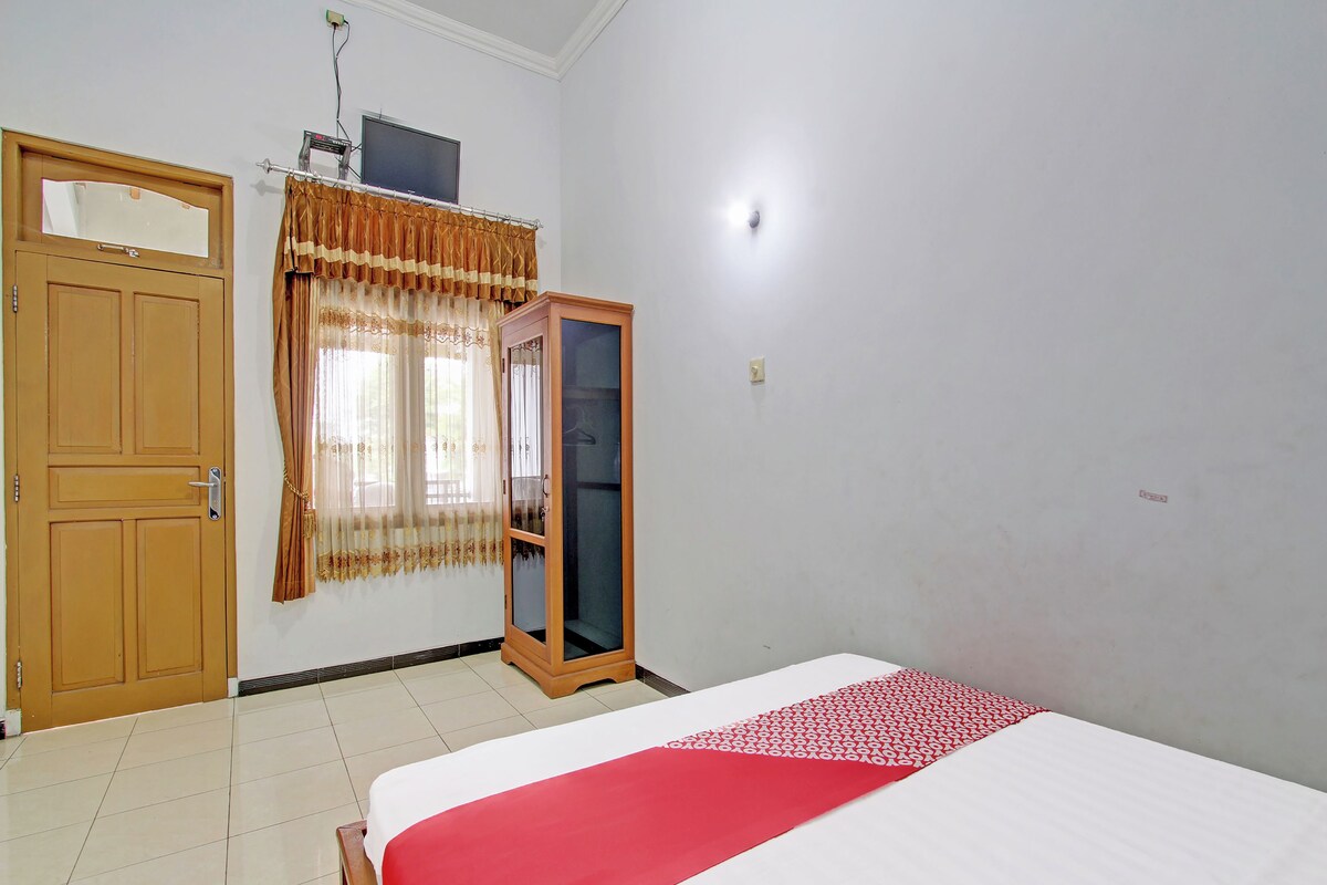 Une chambre à coucher avec un lit, une armoire, une porte et une fenêtre avec des rideaux.