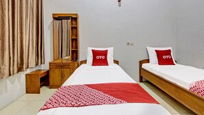 Ein Hotelzimmer mit zwei Einzelbetten, einem Holzschrank, einem Schreibtisch und einem Spiegel.