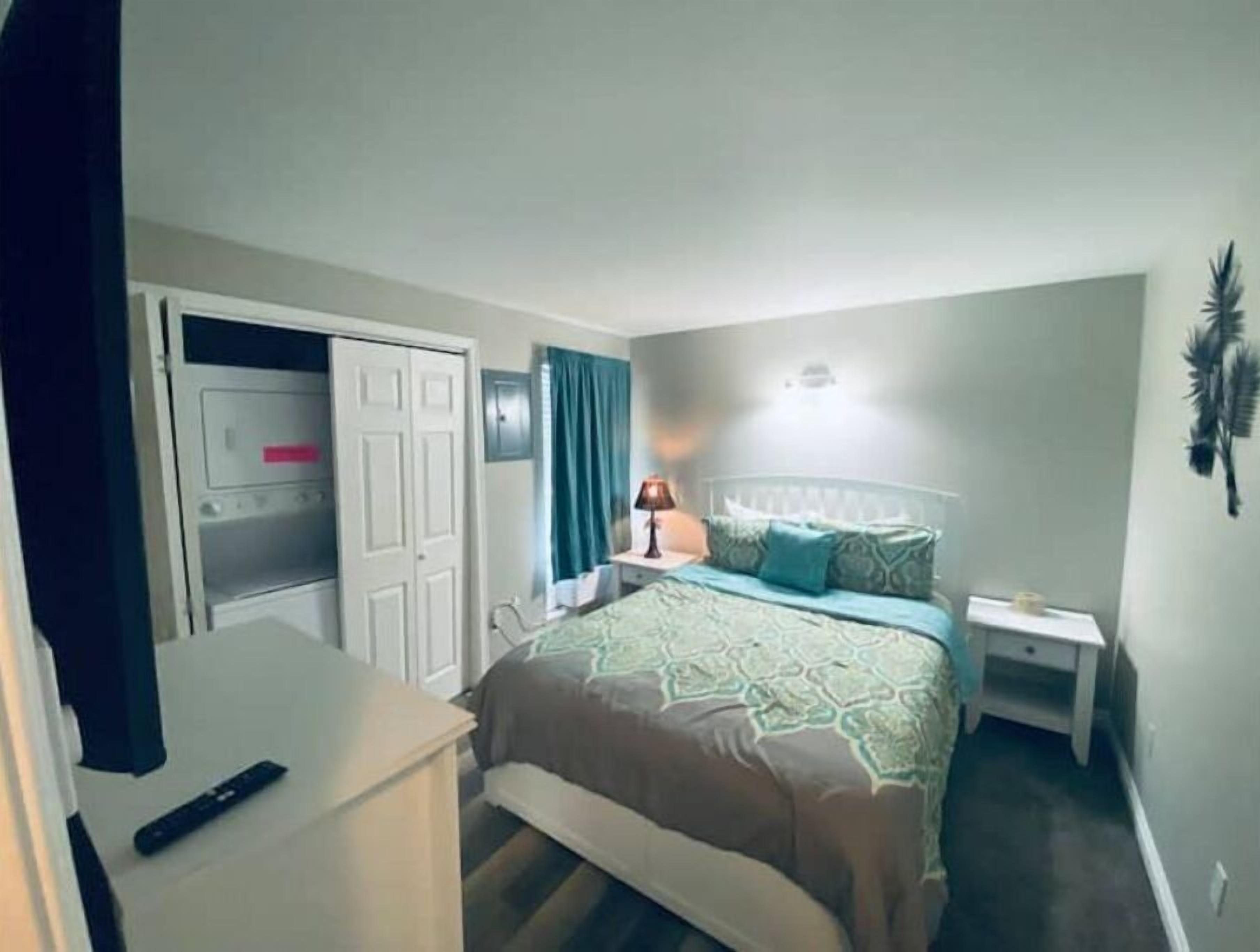 A bedroom with a bed, bedside table, lamp, and a wardrobe.