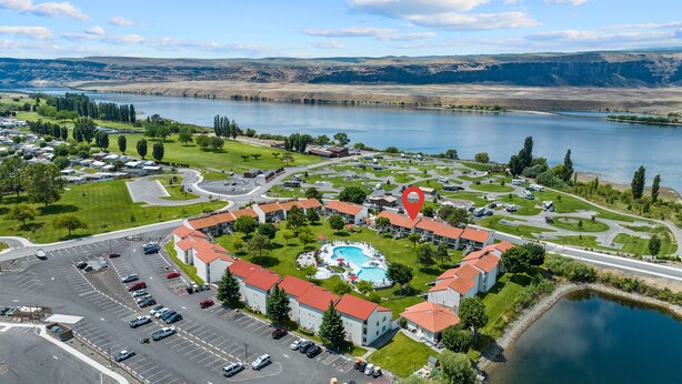 Eine Luftaufnahme eines Resorts mit Schwimmbad, Parkplätzen und einem See.