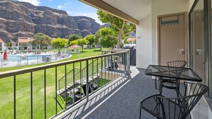 Ein Balkon mit Blick auf einen Swimmingpool, einen Berg und eine Rasenfläche mit einem Gazebo.