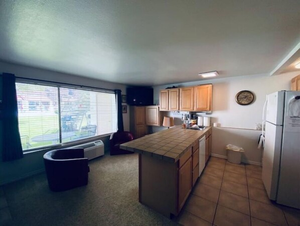 A compact kitchen with a large window, a built-in oven, and a refrigerator.