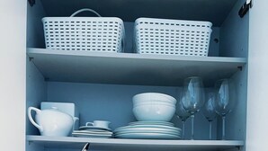 A kitchen with white shelves holding dishes, glasses, and utensils. - Londwell - Luxury Knightsbridge Flat - Harrods (London)