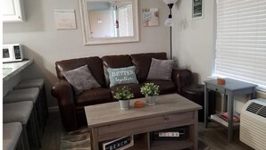 Uma sala de estar aconchegante com um sofá de couro marrom, uma mesa de centro de madeira e uma pequena mesa lateral.