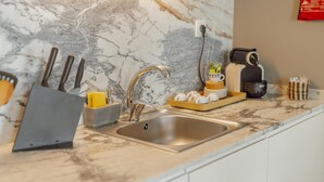 Una cocina con encimera de mármol, pileta de acero inoxidable y diversos utensilios de cocina.