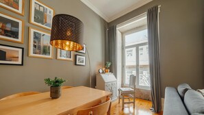 Una sala de estar moderna con una mesa de comedor de madera, un sofá gris y un ventanal con cortinas.
