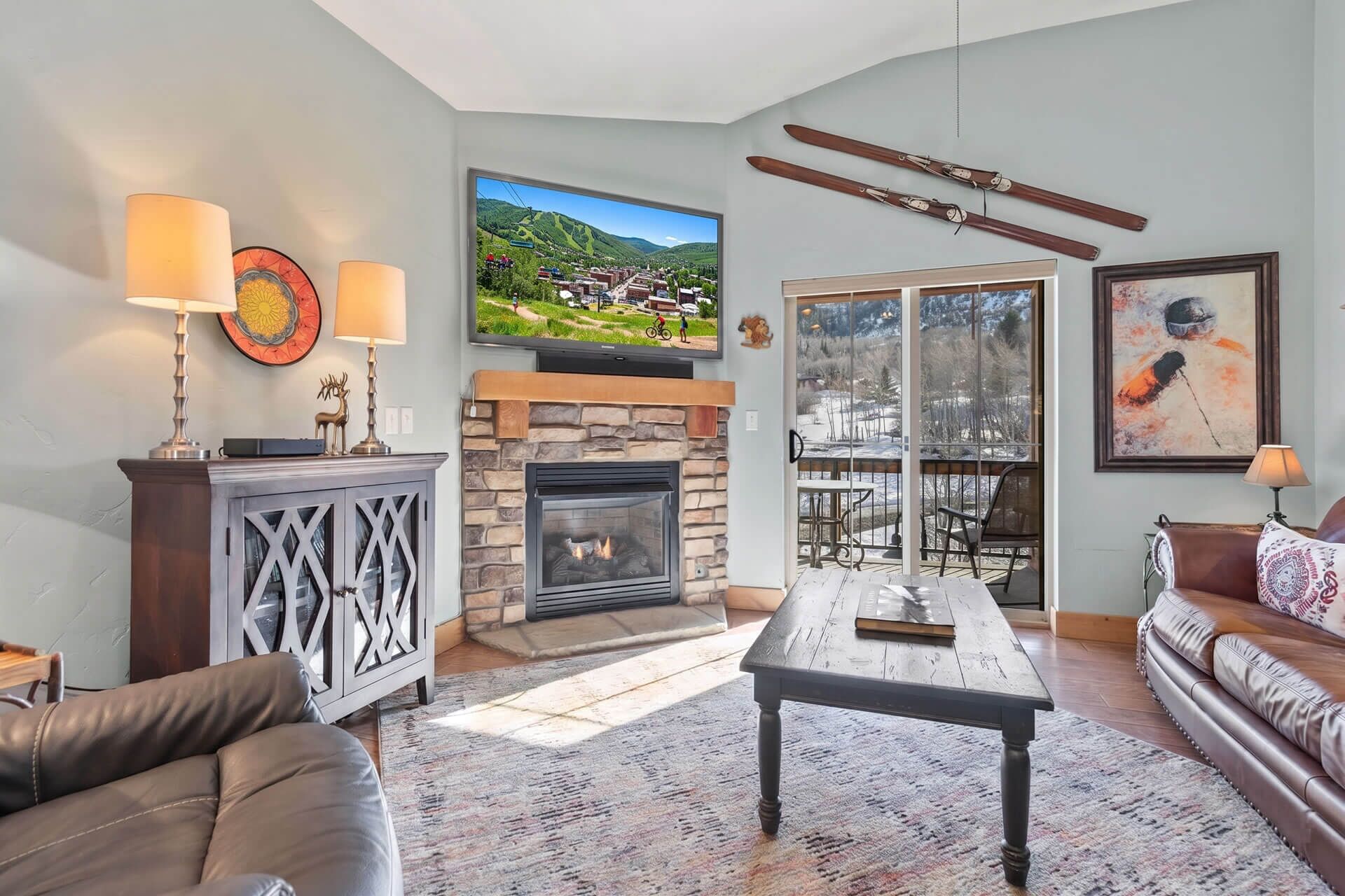 A living room with a fireplace, a television, a ski rack, and a couch.