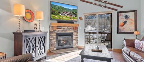 Una sala de estar con chimenea, televisor, un soporte para esquíes y un sofá.