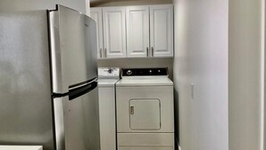 A compact kitchen with a refrigerator, stove, and washing machine. - Minimalist Living 1BR In-Law AC Unit with Private Washer & Dryer (Hayward, California)
