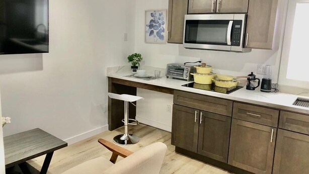 A modern kitchen with wooden cabinets, a microwave, a toaster, and a coffee maker. - Minimalist Living 1BR In-Law AC Unit with Private Washer & Dryer (Hayward, California)