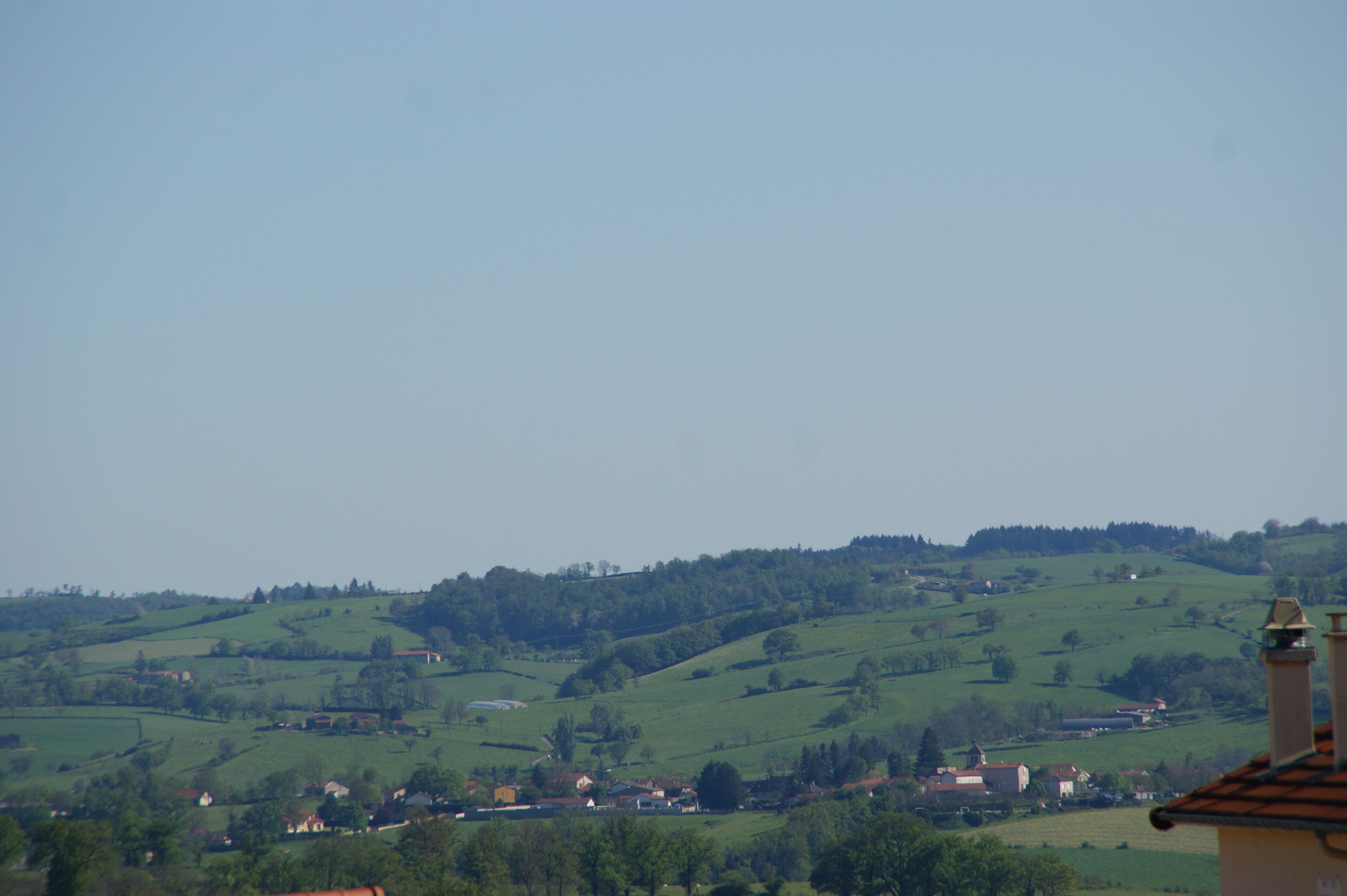 Ländliche Landschaft mit sanften grünen Hügeln und verstreuten Häusern.