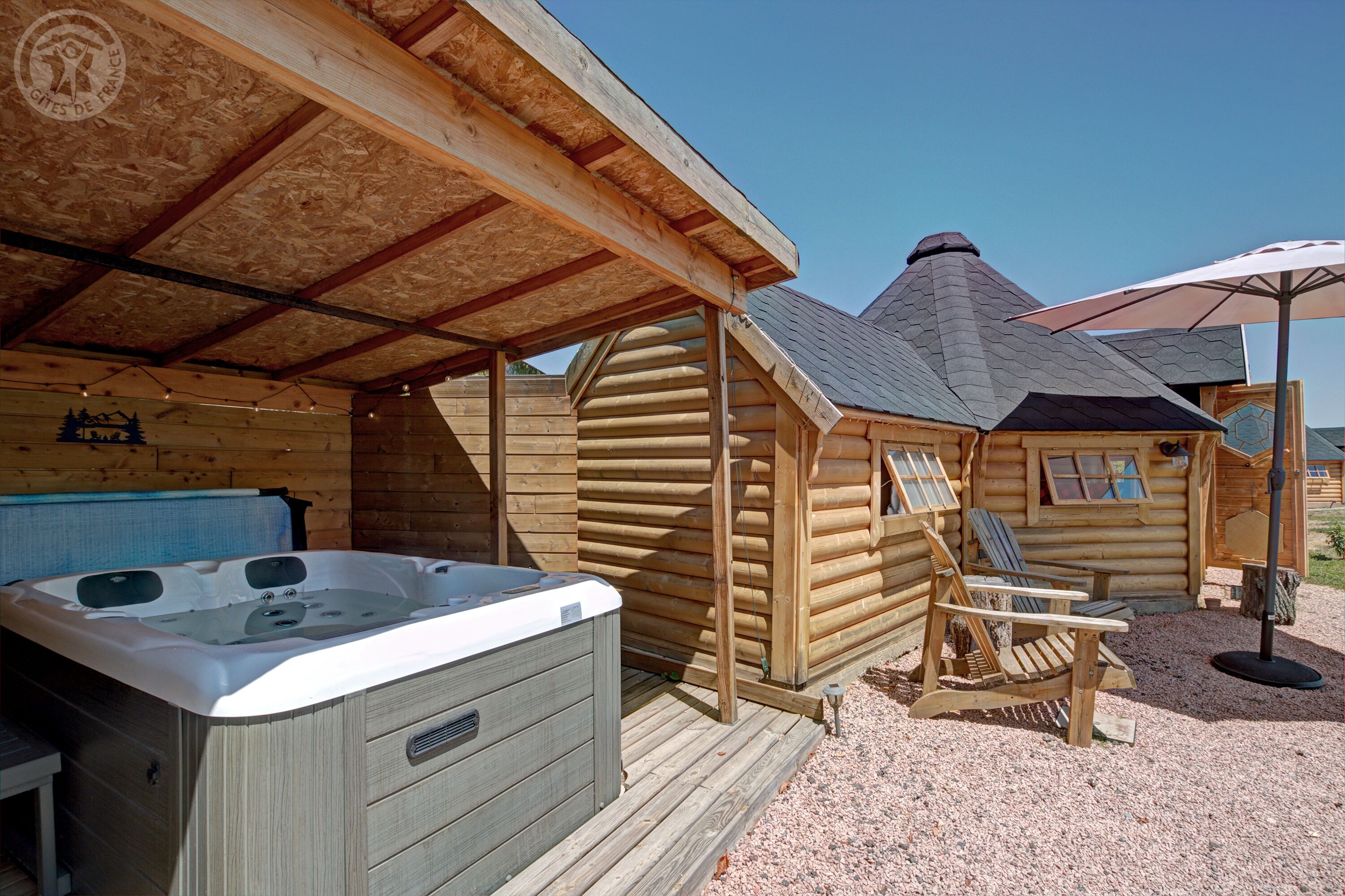 Een houten chalet met een jacuzzi, een overdekt terras en een stoel.