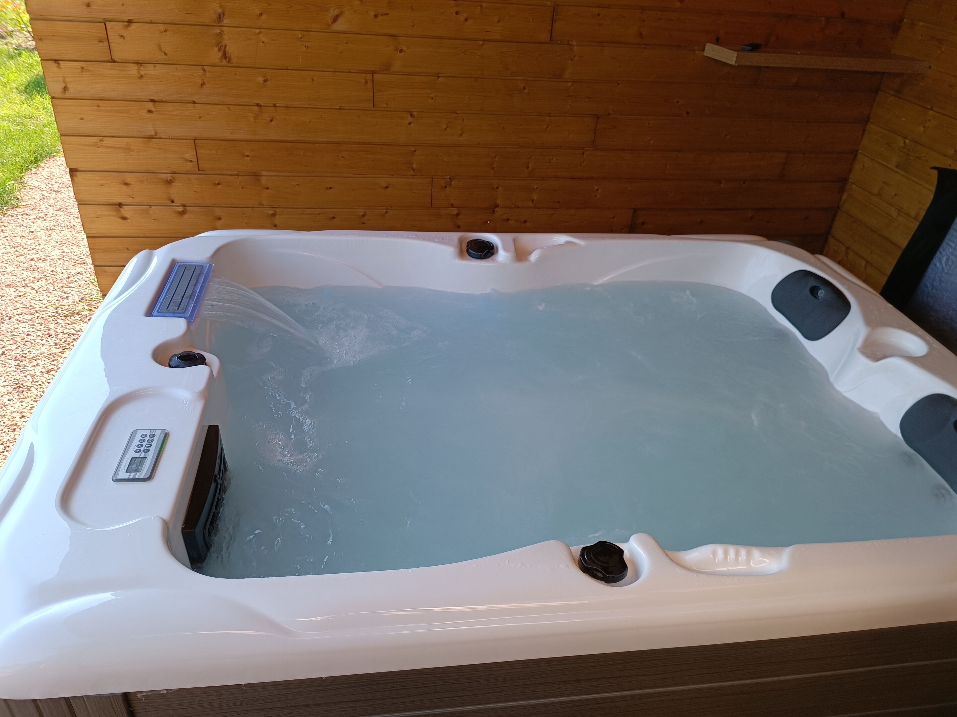 A hot tub with a control panel, two jets, and a drain.