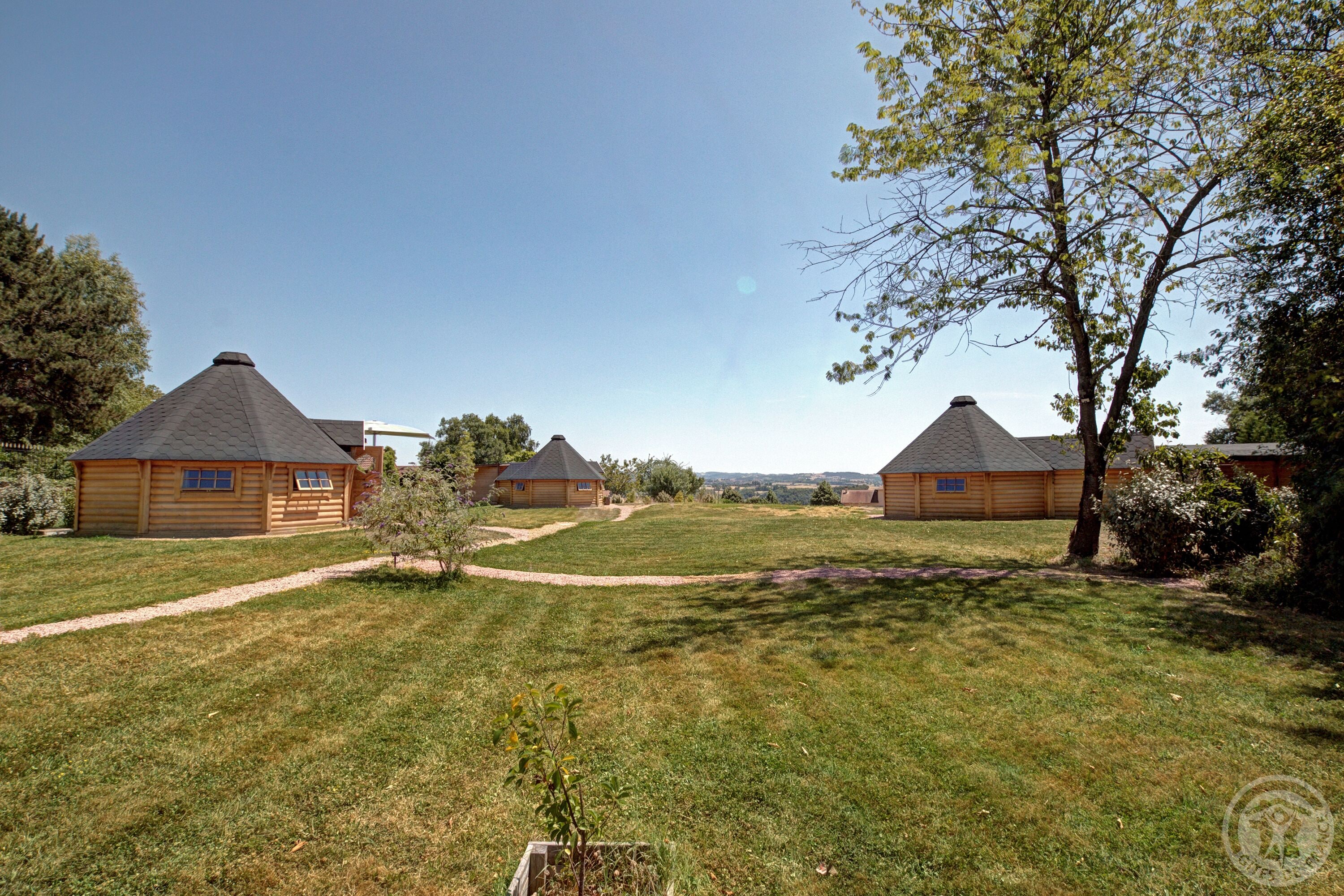 A row of log cabins with a clear sky and a grassy field.
