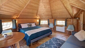 Une chambre confortable dans un chalet en bois, avec un lit, une table à manger et un canapé.