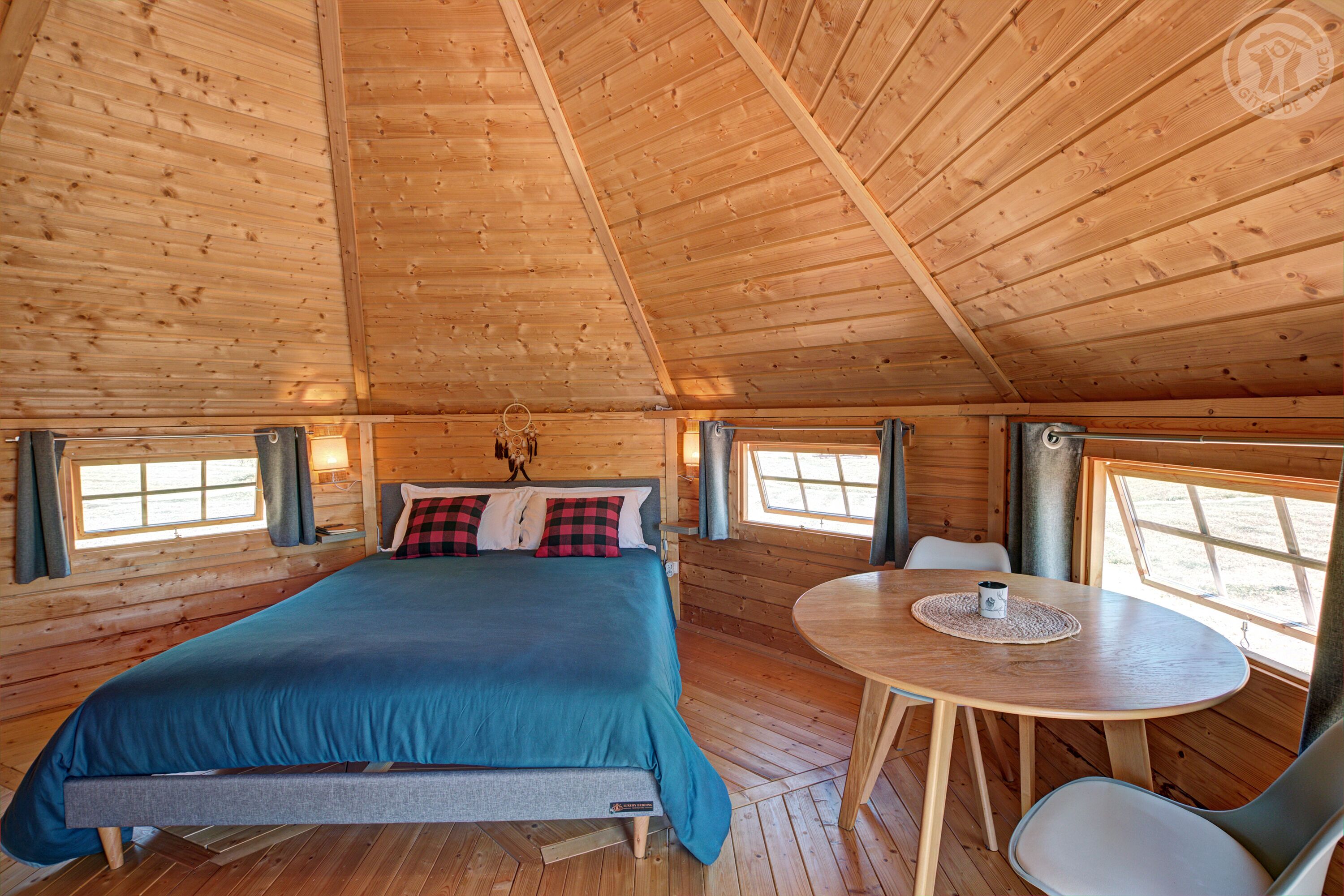Une pièce chaleureuse, aménagée dans un chalet en bois, avec un lit, une table et des chaises.