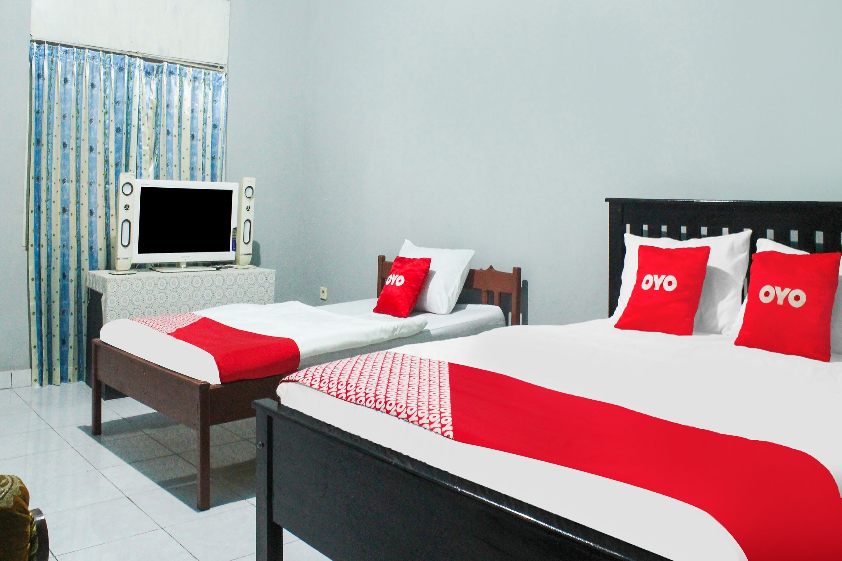 A hotel room with two single beds, a TV, and a small table.
