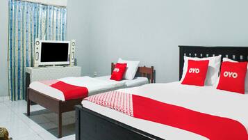 A hotel room with two single beds, a TV, and a small table.