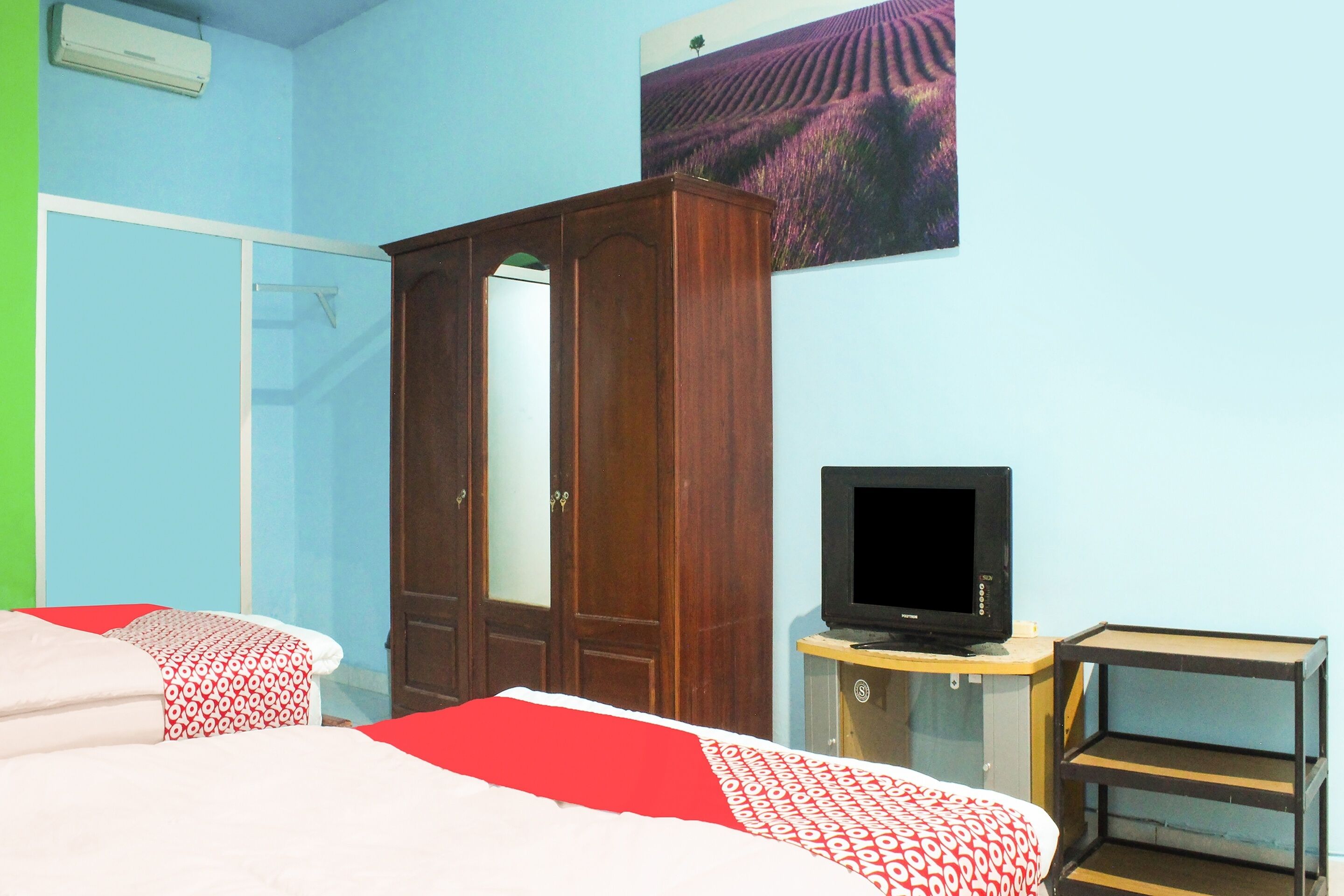Un dormitorio con dos camas, un armario, una televisión y un cuadro en la pared.